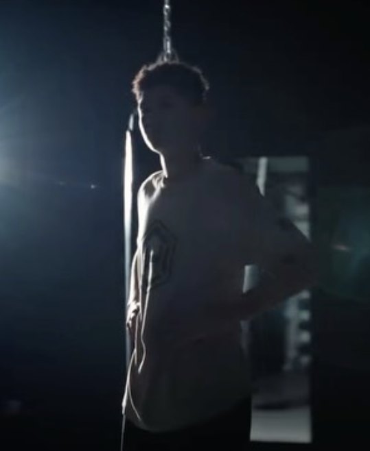 A young athlete silhouetted in a dark gym